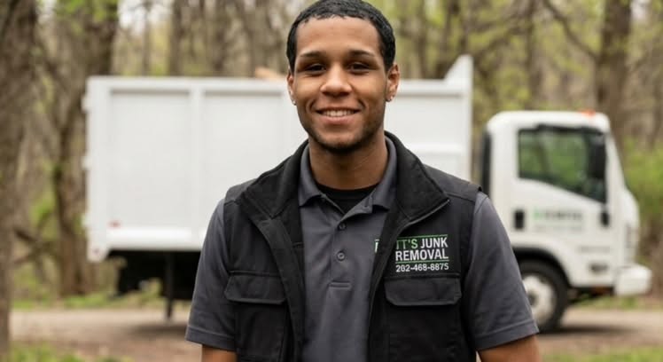 Troy, owner of TT's Junk Removal, standing in front of his dump truck in his branded work vest
